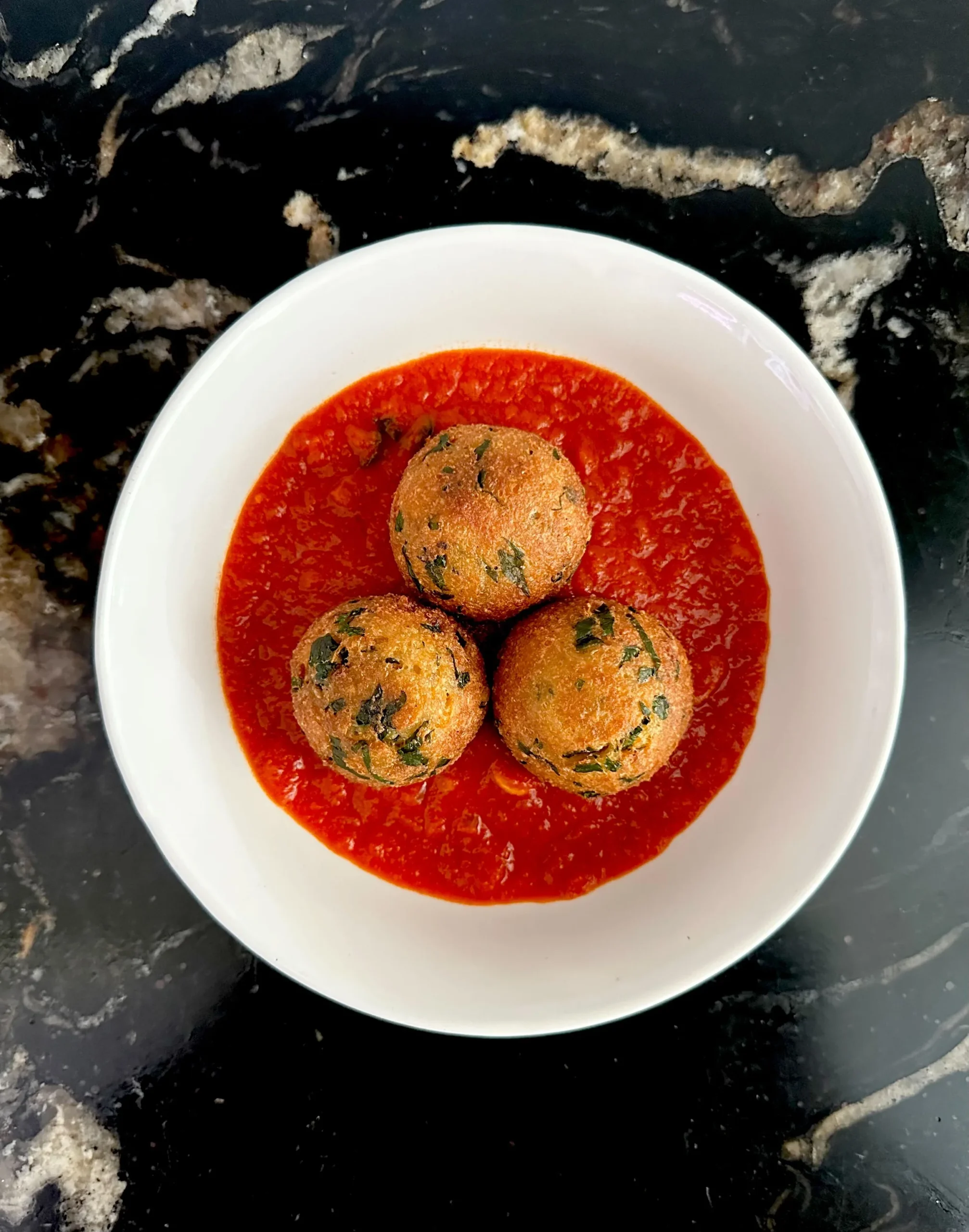 Arancini served over tomato sugo