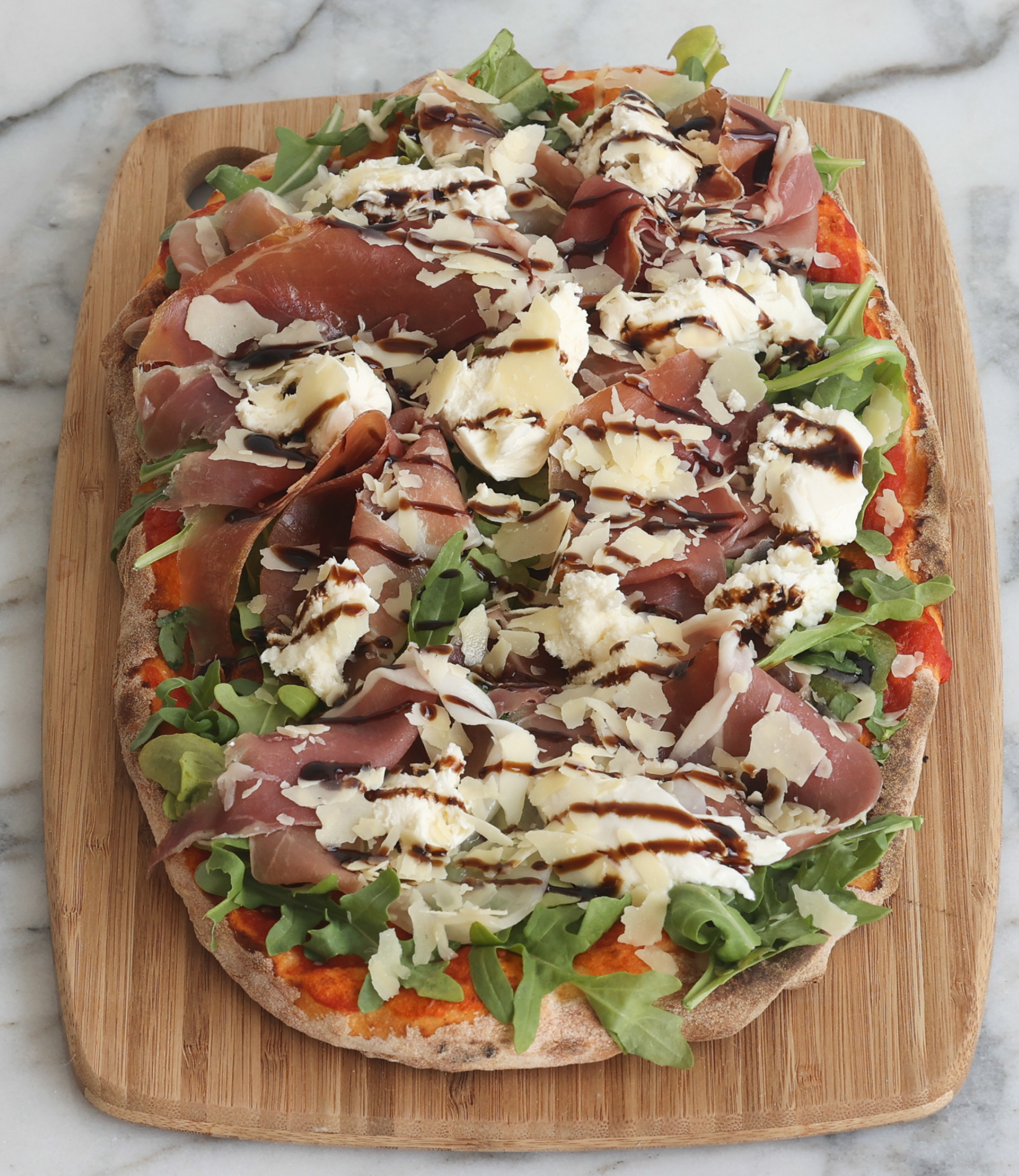 Pinsa with prosciutto, rocket, burrata, parmesan, and balsamic glaze