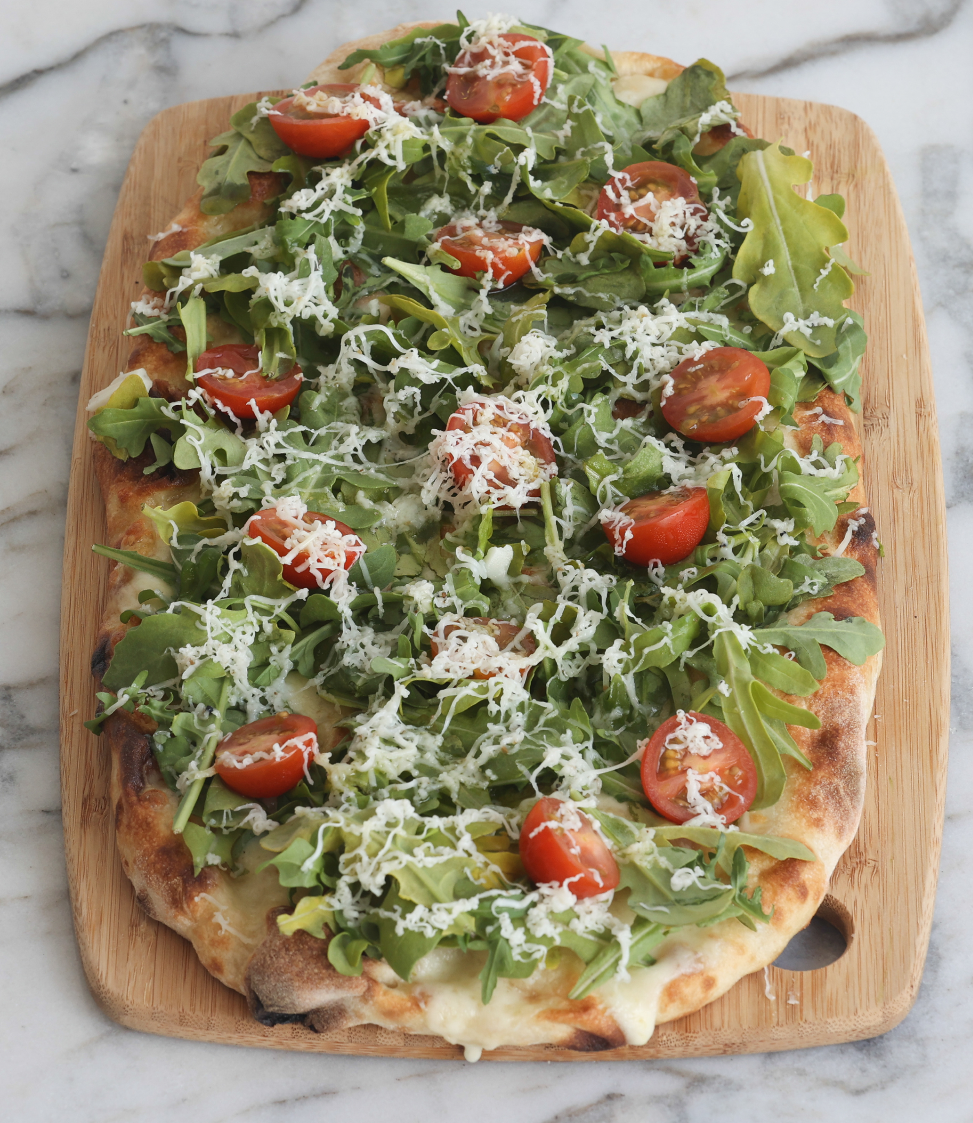 Green pinsa with rocket, cherry tomatoes, and grated cheese
