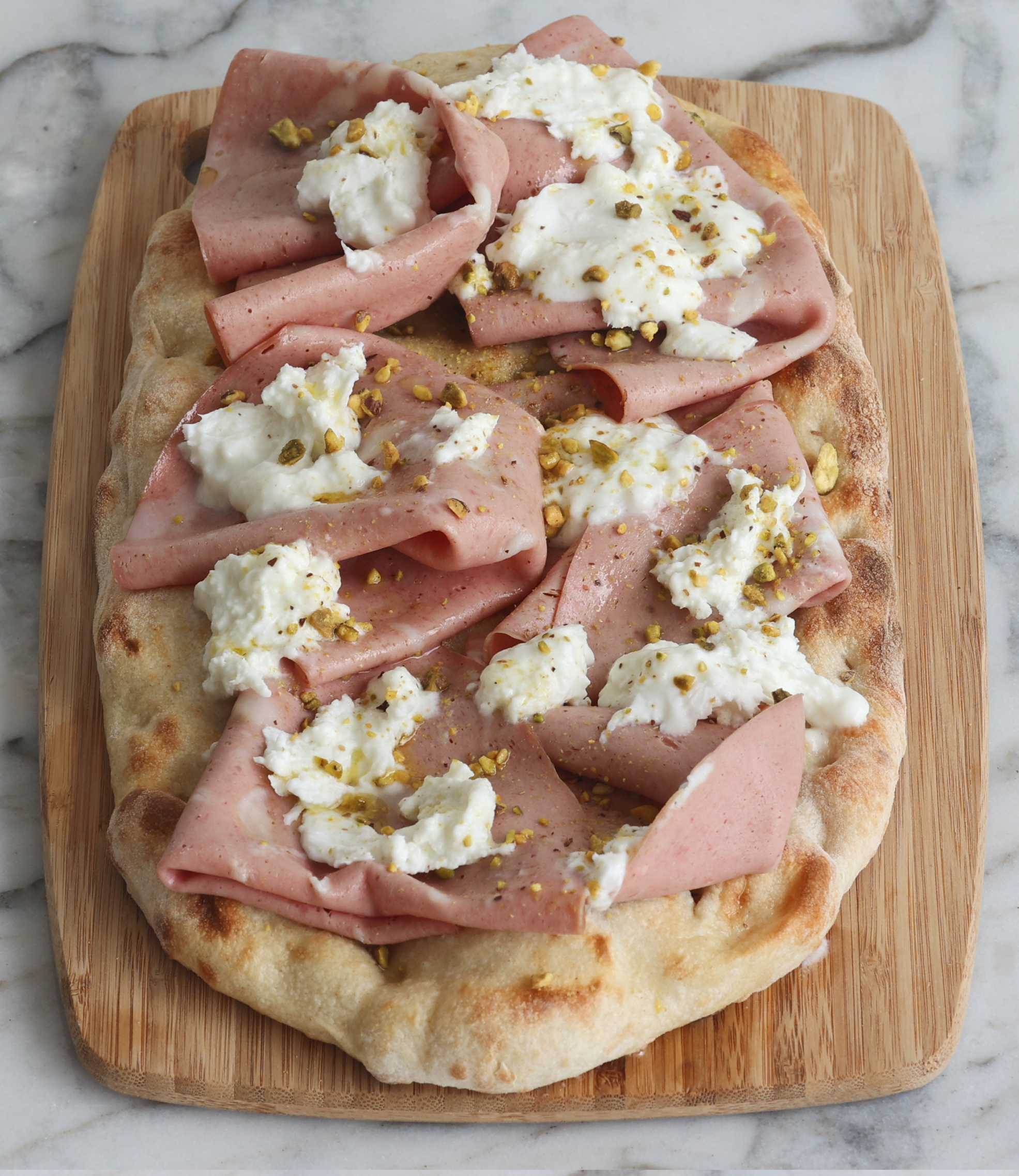 Mortadella pinsa with burrata and pistachio